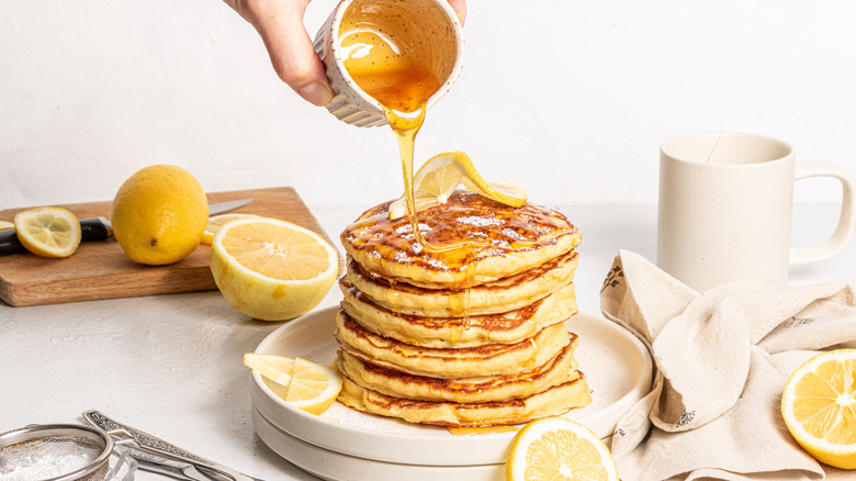 Pouring honey over stack of pancakes