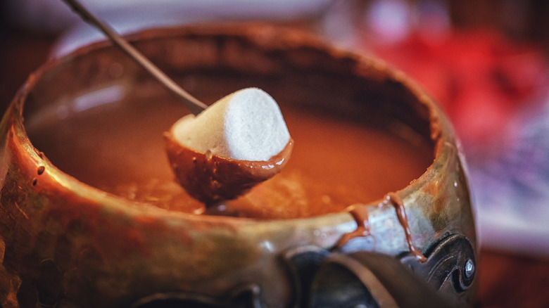 marshmallow being dipped in chocolate fondue