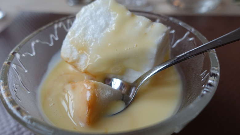 A floating island in glass dessert bowl, a spoon resting in it