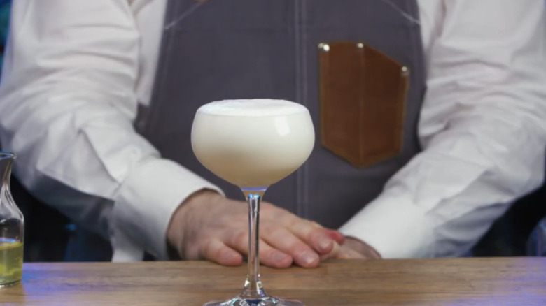 A mixologist stands behind a punch à la romaine in a coupe glass.