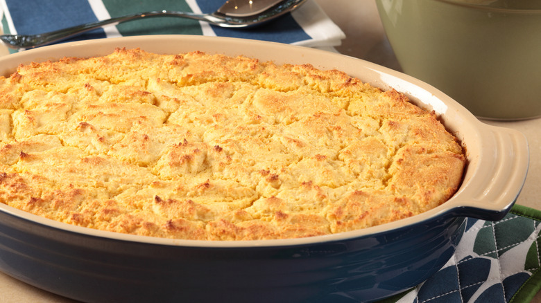 A casserole dish filled with chicken cornbread casserole next to some spoons