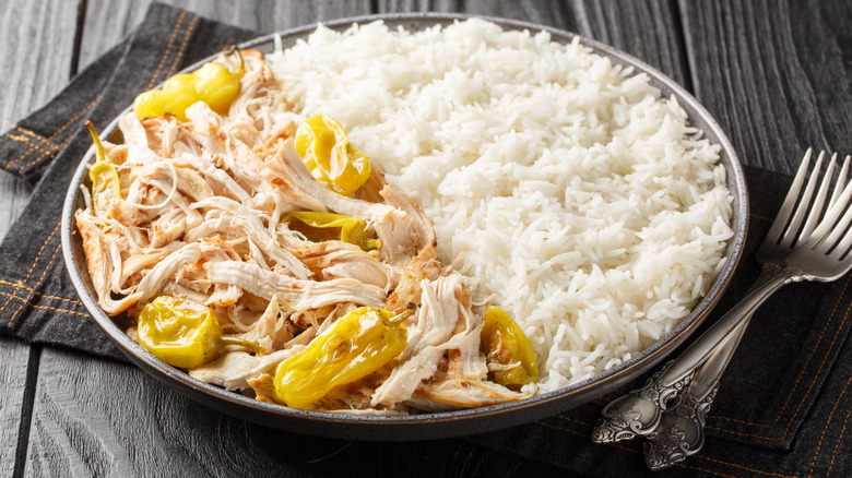 A plate with Mississippi chicken and white rice next to two forks