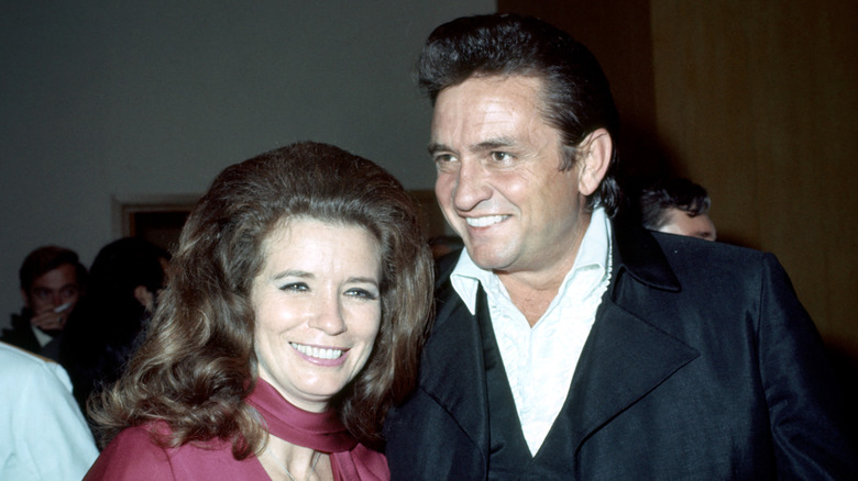 June Carter Cash and Johnny Cash smiling together looking to the side of the camera