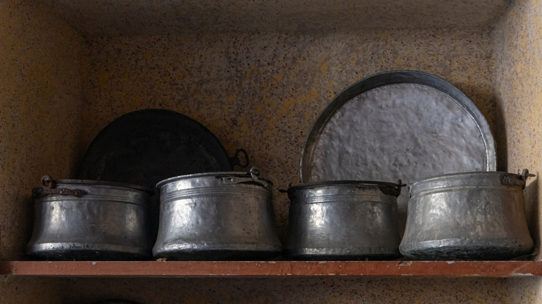 Antique pots and pans on a rustic shelf.