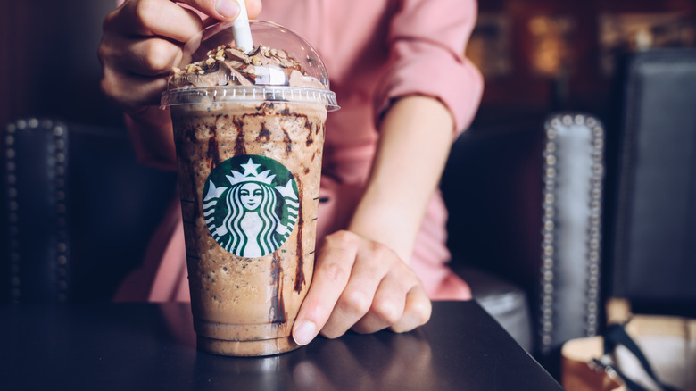 customer holding a Starbucks frappuccino on a table