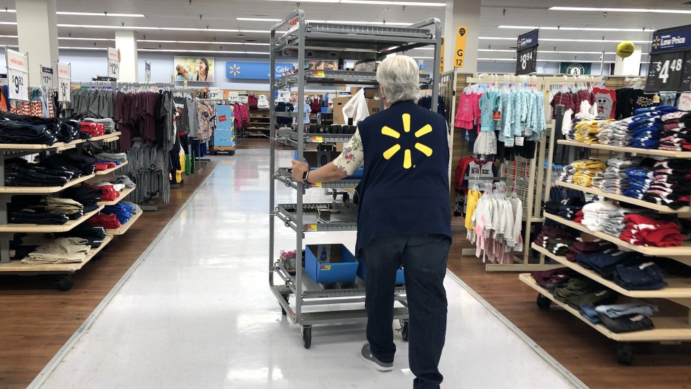 Walmart employee pushing cart through store