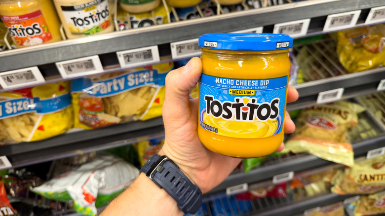 Hand holding nacho cheese dip