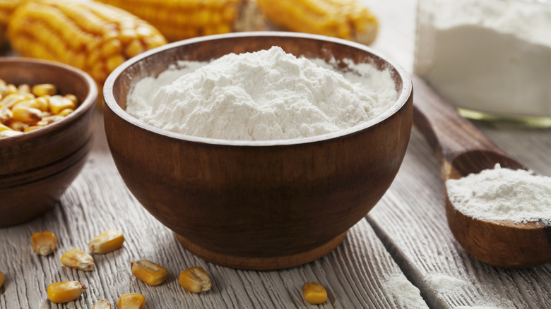 Wooden bowl of cornstarch with corn kernels around it