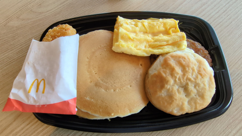 Breakfast platter from McDonalds with hash brown, pancakes, eggs, biscuit, sausage