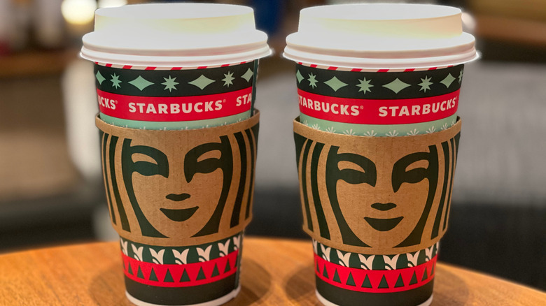 Two Starbucks holiday cups on a table