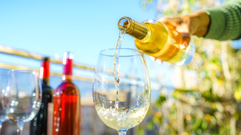 A white wine with stunning clarity being poured from the bottle into a glass.