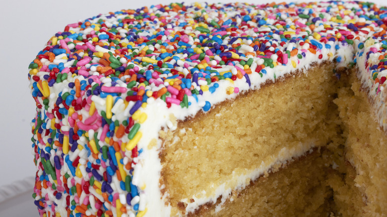 A close-up shot of a cut cake covered in sprinkles