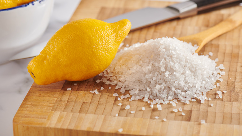 A lemon and salt on a wooden cutting board