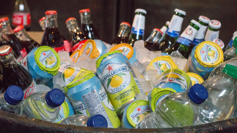 Tub filled with water, flavored water, beer, and soda bottles and cans on ice.