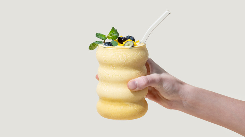 Hand holding creamy smoothie in glass