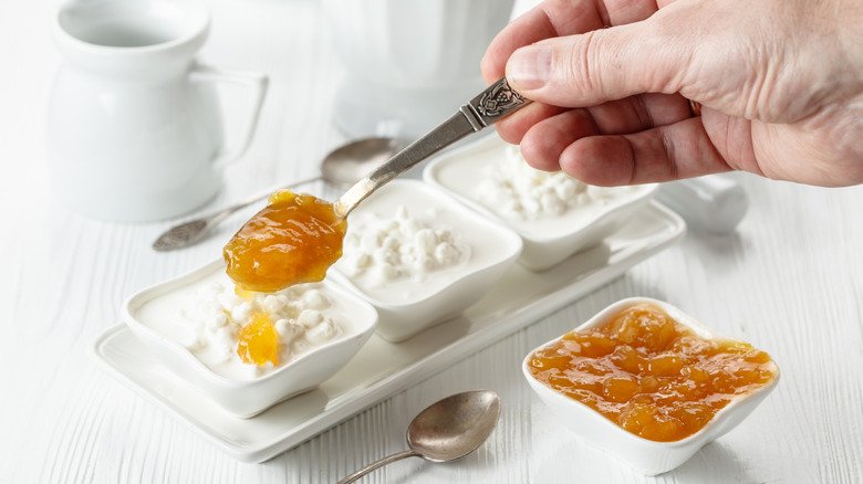Hand spooning cottage cheese onto apricot jelly