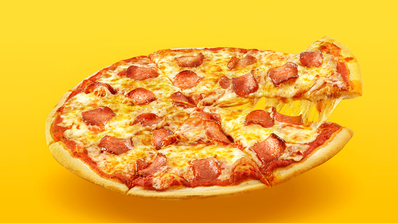 A cheesy pepperoni pizza on a yellow background