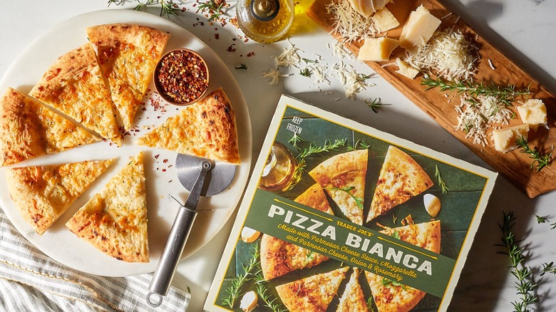 Sliced frozen white pizza next to the pizza box on a white tabletop