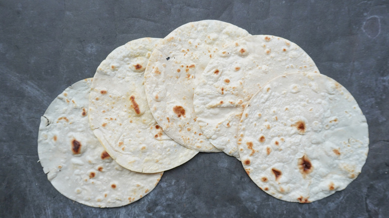 five tortillas spread out on slate surface