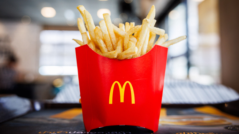 A red container of McDonald's French fries on a table with a blurred background