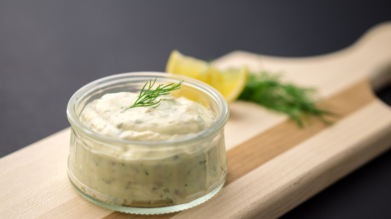 Glass jar of tartar sauce sitting on a wooden board