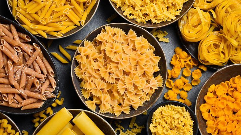 A selection of dried pasta shapes in black dishes