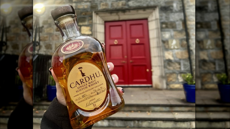 Bottle of Cardhu single malt scotch held up outside the distillery