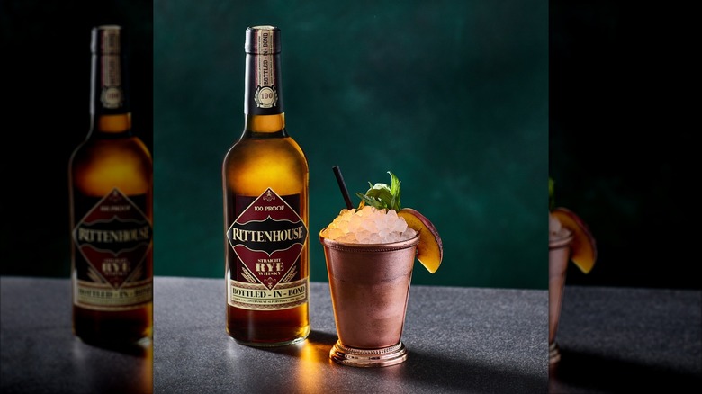 bottle of Rittenhouse Rye next to a cocktail in a copper cup