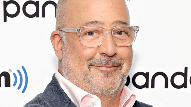 Andrew Zimmern smiling in clear-rimmed glasses