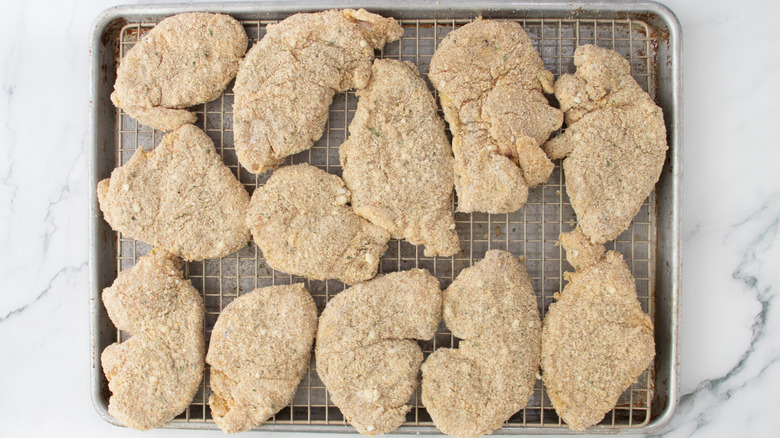 breaded chicken on a wire rack in a pan