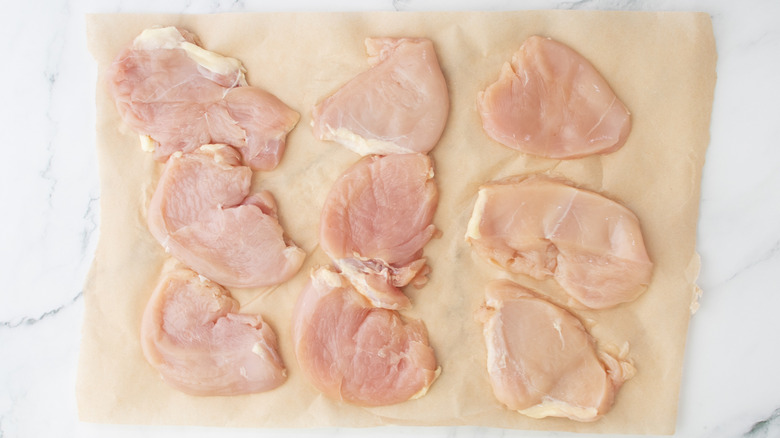 flattened chicken pieces on brown paper