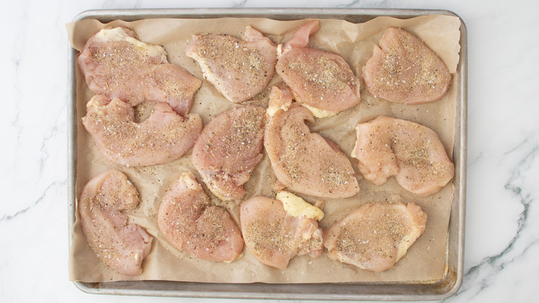 seasoned flattened chicken pieces on brown paper