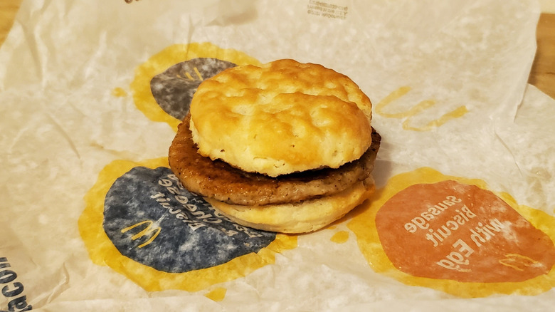 A biscuit stuffed with one sausage patty sits on a McDonald's wrapper.