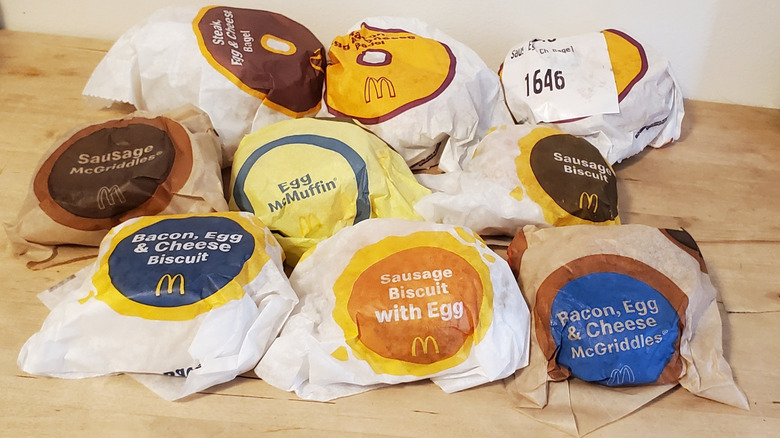 A pile of nine McDonald's breakfast sandwiches, still in their paper wrappers.
