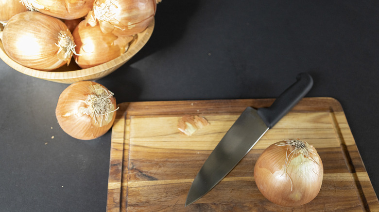 Bowl of onion next to cutting board with a knife and onion