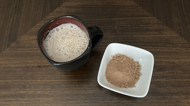 Cup of hot chocolate with a bowl of baking cocoa powder
