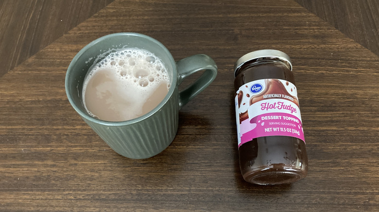 Cup of hot chocolate with a jar of hot fudge sauce