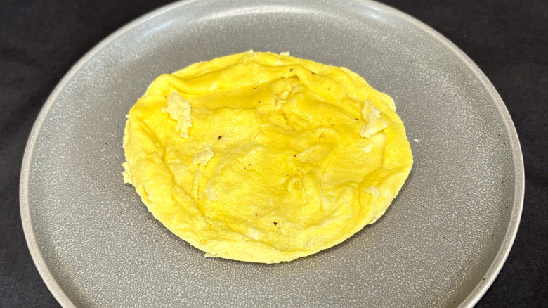 Round scrambled eggs on grey plate