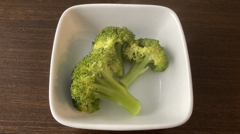 White bowl of roasted broccoli florets