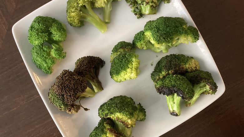 Broccoli cooked using various methods on a white plate