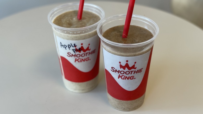 a pair of smoothies held up outside a shop