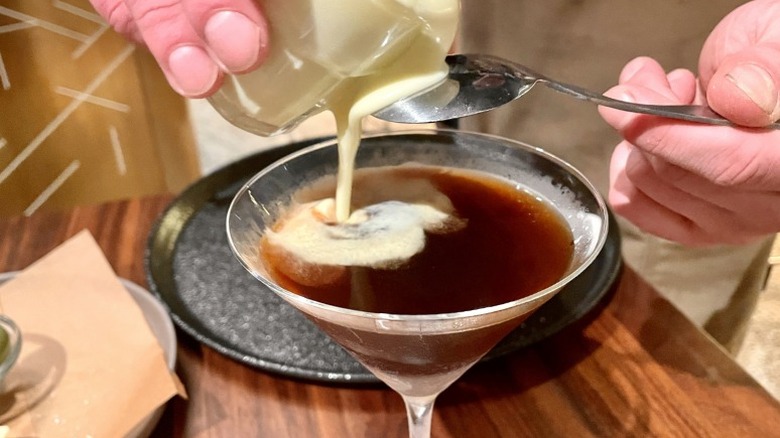 A barista finishing an espresso martini with Oleato cream