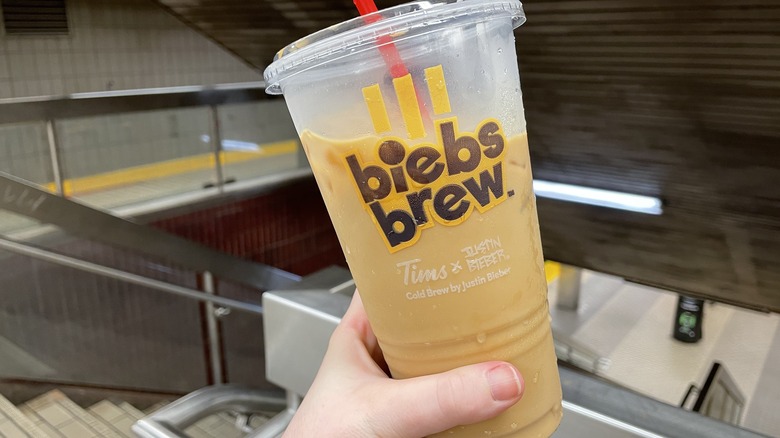 a hand holding a large cup of biebs brew 