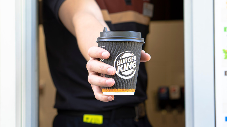 worker holding Burger King coffee cup