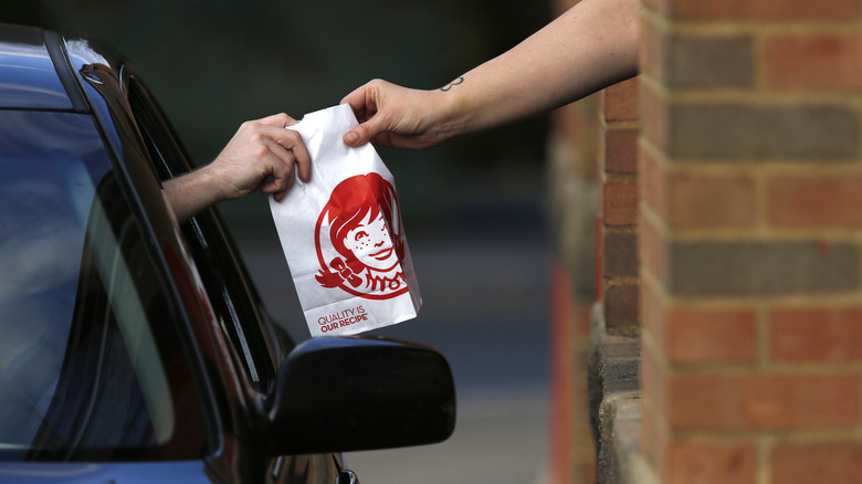 Wendy's employee passing food to a customer in the drive-thru