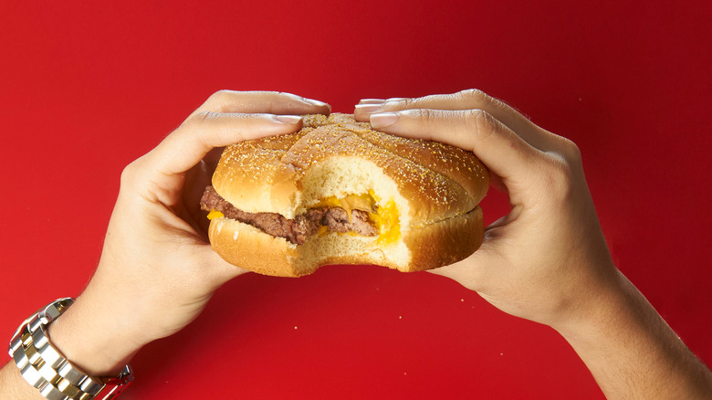 Two hands holding cheeseburger