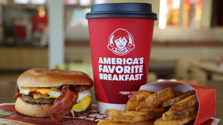 A Wendy's coffee cup that reads "America's Favorite Breakfast" sits next to a breakfast sandwich and fries