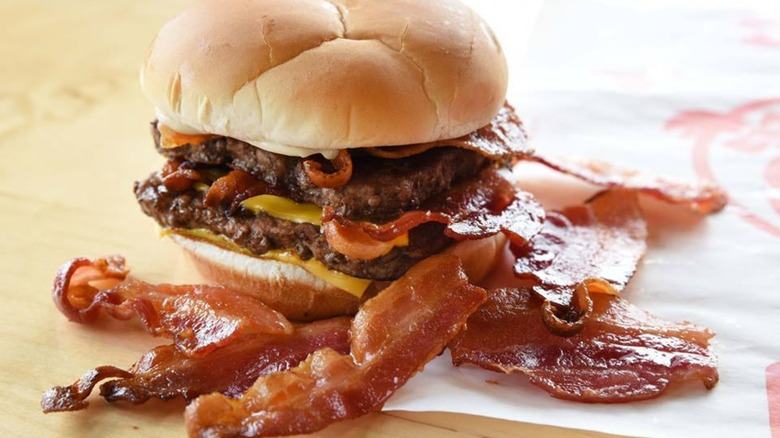 Wendy's Baconator cheeseburger sits next to strips of bacon