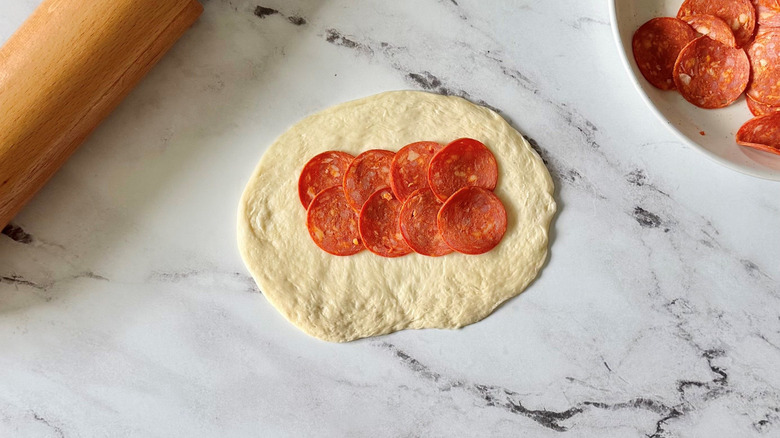Rolled out dough with pepperoni slices on top