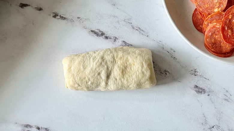 Rolled up dough next to pepperoni